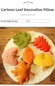 Colorful leaf-shaped plush cushions with embroidered smiles arranged on a white rug