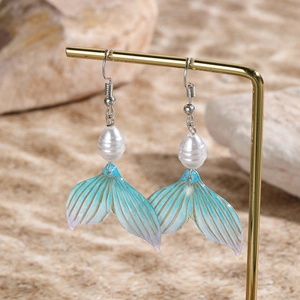 Macro shot of fishtail earrings with blue gold gradient and white pearl details