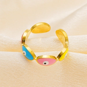 Detail of golden stainless steel eye ring with colorful enamel inlay on silk background