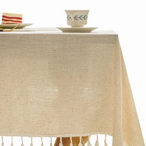Beige cotton linen tablecloth with elegant fringe tassel edges and striped pattern texture