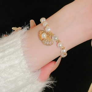 Detail of adjustable pearl bracelet with zircon-encrusted gold shell charm on wrist