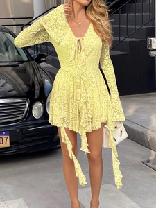 Détail d'une mini-robe en dentelle jaune à manches longues avec col en V et nœud frontal