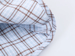 Detailed close-up of light blue plaid fabric showing hem stitching and textile texture