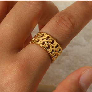 Macro detail of a double-layered gold chain link ring on a finger with a luxury aesthetic