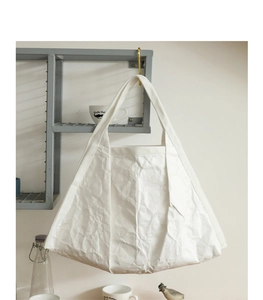 Detail of white wrinkled paper texture tote bag hanging on a minimalist metal shelf