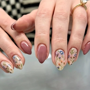 Close-up of almond press-on nails featuring dusty rose color and floral pattern detail
