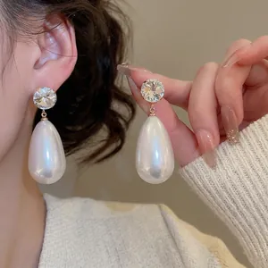 Elegant gold drop earrings featuring large round crystals and white teardrop pearls