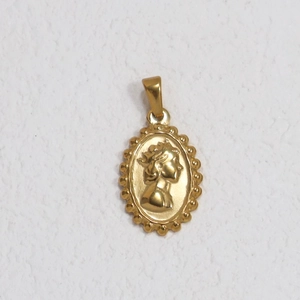 Detailed macro view of an oval gold-plated queen portrait relief pendant with beaded edge