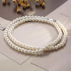 Détail d'un collier de perles à double rangée avec fermoir en acier inoxydable noué