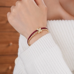 Detail view of double-layer bracelet with red leather cord and gold zircon cross clasp