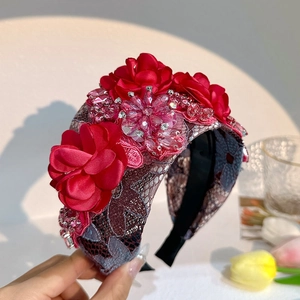 Detail of red satin flowers and crystal beads on a lace headband for women