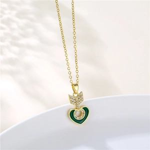 Detailed shot of golden arrow and green heart pendant with zircon on a white bowl