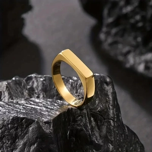 Polished gold rectangle signet ring made of stainless steel on a dark volcanic rock