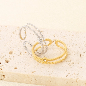 Detail of gold and silver wavy beaded rings with white rhinestones on stone surface