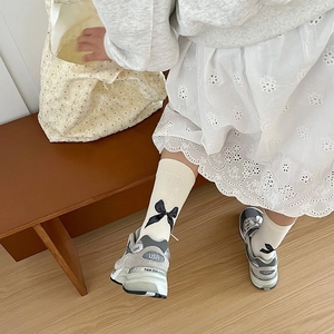 Japanese style cream white crew socks with a large black bow paired with grey sneakers