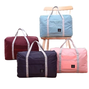 Set of four colorful foldable travel bags in blue, red, navy, and pink with sturdy handles