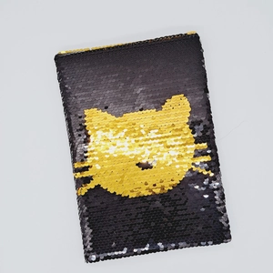 Dettaglio di un taccuino creativo con paillettes reversibili e motivo a gatto nero e oro