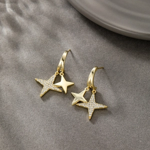 Detailed macro view of 14K gold-plated double star earrings with sparkling zircons