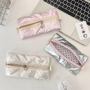 Detail of glossy ribbon pattern pencil cases with floral zipper pull and polka dot lining