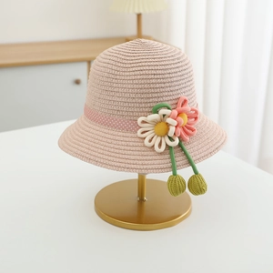 Detail of pink straw sun hat for girls with handmade floral knit decor and polka dot ribbon