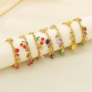 Fruit themed charm bracelets with colorful strawberry and cherry enamel pendants on gold chains