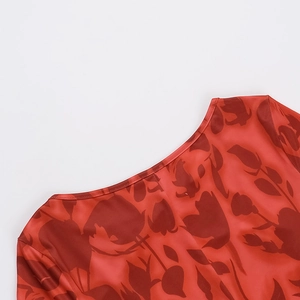 Detailed view of the elegant round neckline and red floral print on silky satin fabric