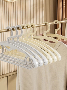 Close-up of non-slip curved hangers in beige and grey with a space-saving seamless design