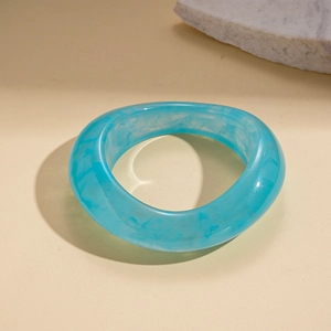 Detail of light blue resin bangle with marble texture on beige textured background