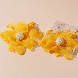 Detailed shot of yellow handmade lace flower earrings with elegant pearl center stamen