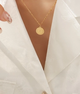 Dettaglio di una collana dorata con ciondolo a stella indossata da una modella