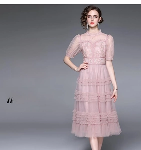 Détail de broderie en dentelle rose et robe en tulle à volants avec col montant