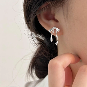 Close-up of elegant silver bow stud earrings worn by a model in a minimalist style