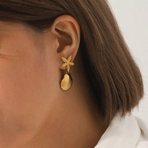 Close-up of a model wearing golden starfish and shell dangle earrings made of stainless steel