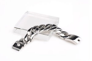 Polished silver titanium steel Cuban link bracelet displayed on a clear acrylic block