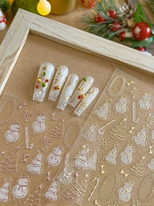 Macro view of 3D Christmas nail stickers with gold embossed snowman and tree patterns