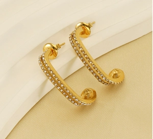 Macro detail of J-shaped gold double-layer earrings with sparkling rhinestones inlays