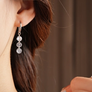 Close-up of minimalist tassel earrings with three cubic zirconia stones worn by a model
