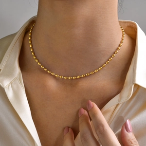 Close-up of golden titanium steel rice bead necklace worn on neck as layered jewelry