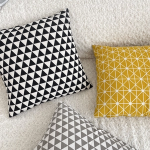 Detail of geometric pattern cotton linen pillow covers on a soft bouclé white sofa