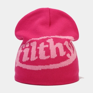 Close-up of pink knitted beanie featuring jacquard filthy text and thick ribbed texture