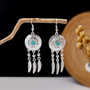Detailed close-up of bohemian dreamcatcher earrings with turquoise and feather pendants