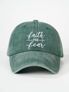 Detailed close-up of FAITH OVER fear embroidery on a dark green washed cotton baseball cap