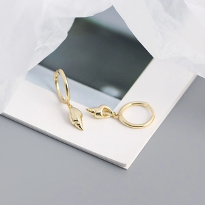 Detailed view of gold hoop earrings with conch shell pendants on a white book