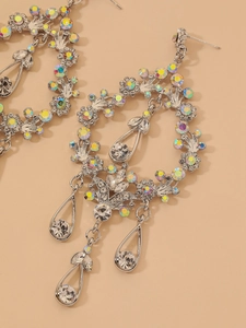 Close-up of silver drop earrings with floral wreath design and sparkling rhinestones