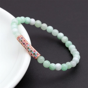 Macro detail of light green stone beads with a rose gold pavé zircon cylinder bead