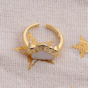 Macro detail of a gold cloud-shaped adjustable ring with white enamel inlay on star fabric