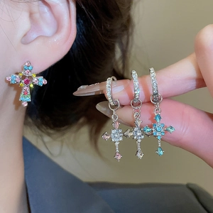 Detailed macro of silver cross earrings featuring vibrant colorful crystal stones