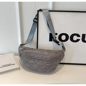Gray quilted crossbody chest bag with adjustable strap displayed on a white table
