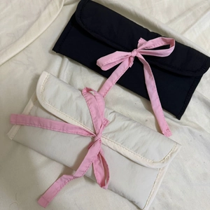 Vue à plat de pochettes à papeterie matelassées noires et crème avec nœuds en ruban rose
