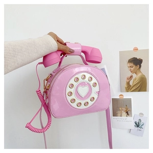 Detailed close-up of a pink retro telephone crossbody bag featuring a handset top handle